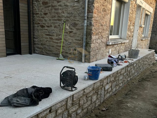 Terrasse dallée en pierre avec muret de soutènement
