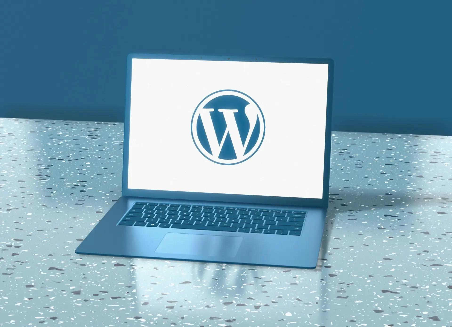 Notebook exibindo logo do WordPress na tela sobre mesa azul
