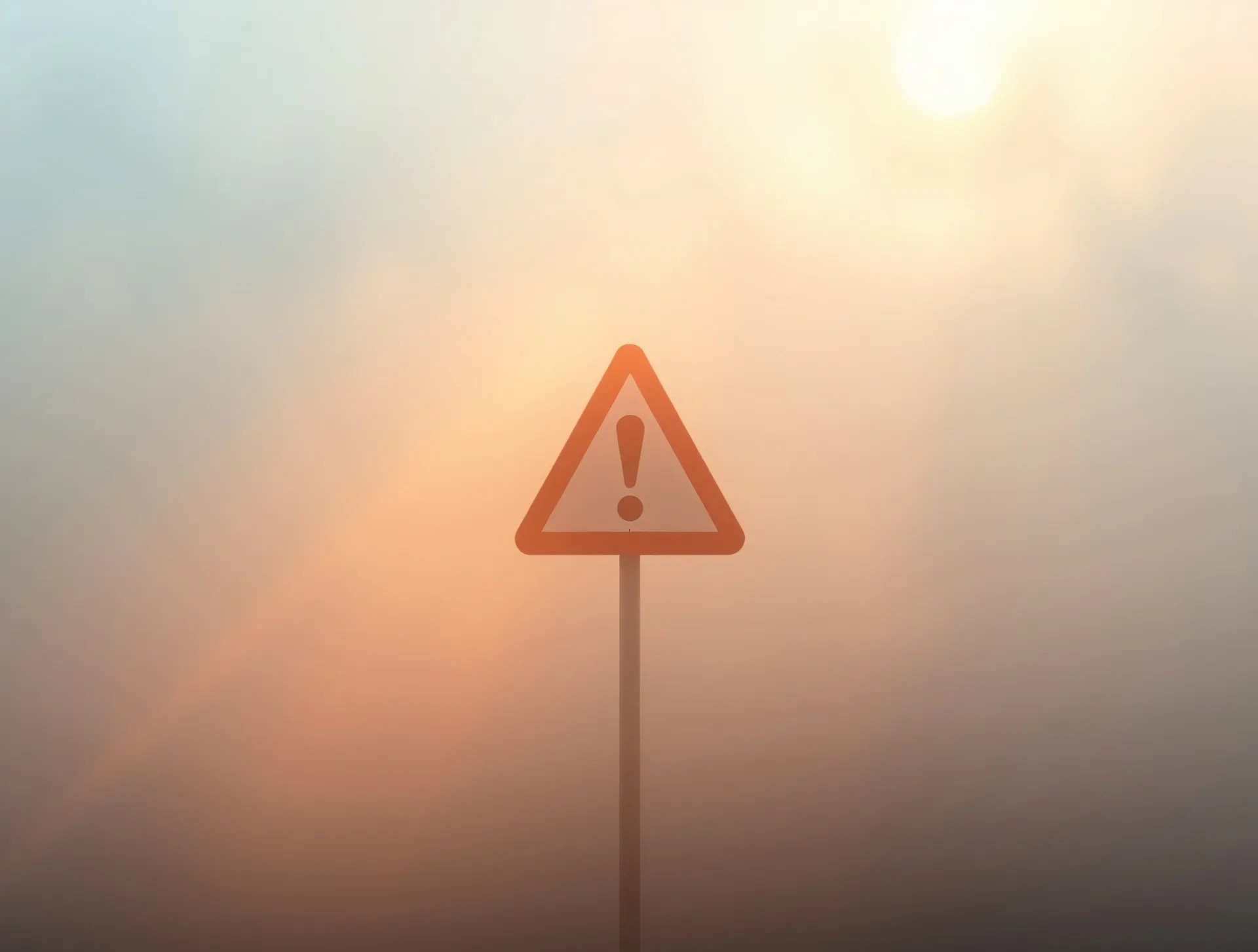 Placa triangular de alerta com exclamação em cenário de neblina densa e luz solar dourada difusa