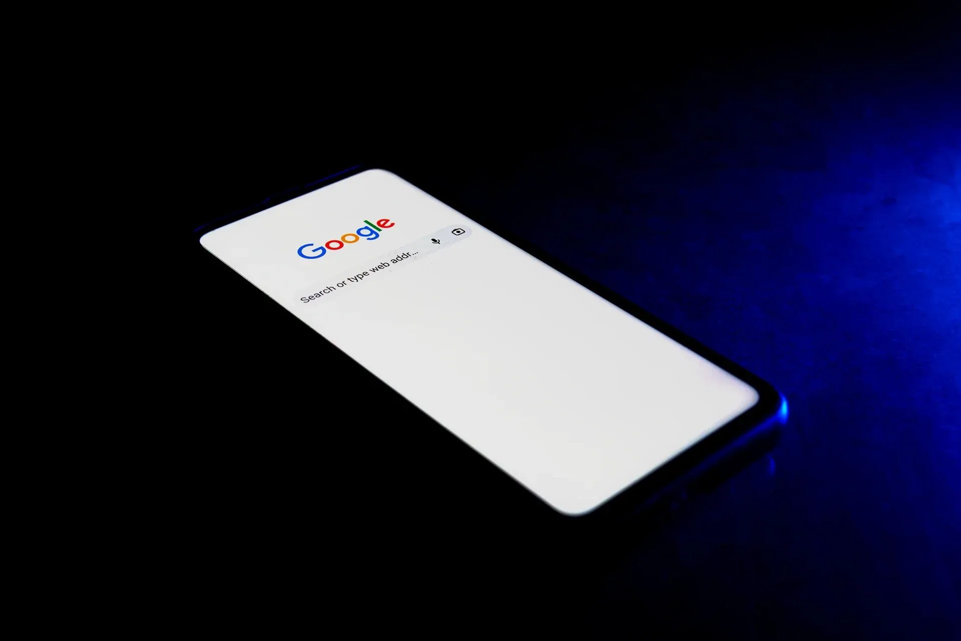 Celular exibindo a página de pesquisa do Google em ambiente escuro