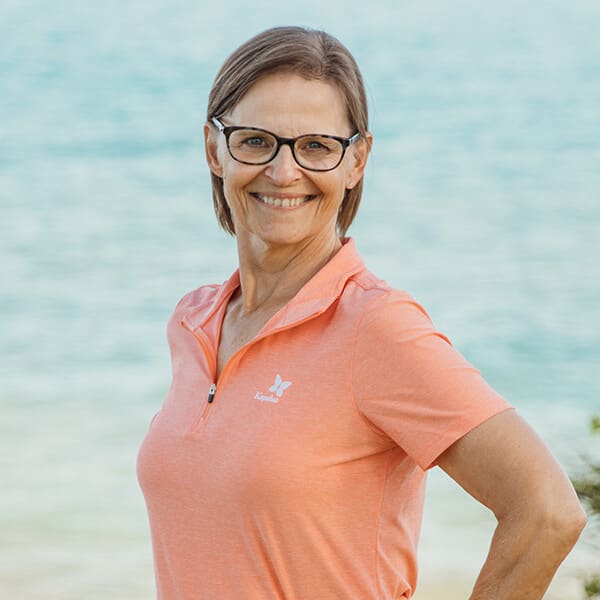 Tammy_Cropped Tammy Gibson standing in front of water with a coral colored polo shirt on