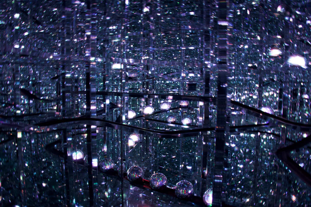 Visitors walking through the glowing Microcosmos installation at TeamLab Borderless