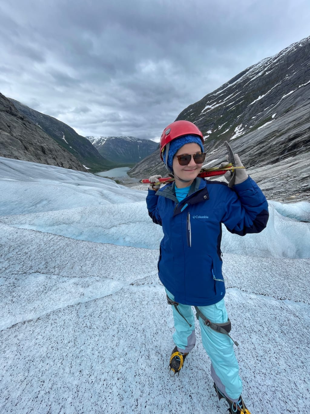 Wearing a helmet, harness, crampons, and holding an ice axe before ice climbing