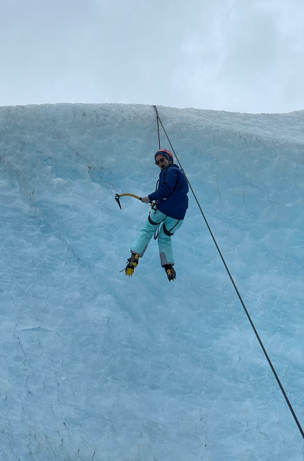 Ice climber hanging from the rope after slipping on the wall