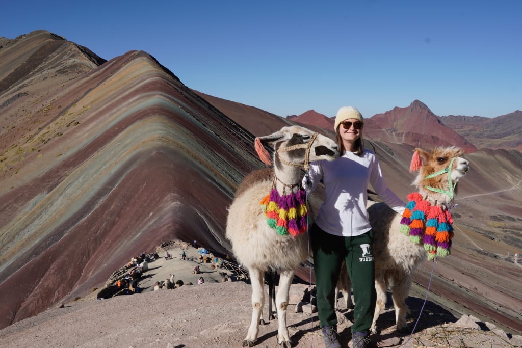 Kathryn posing with llamas at Rainbow Mountain