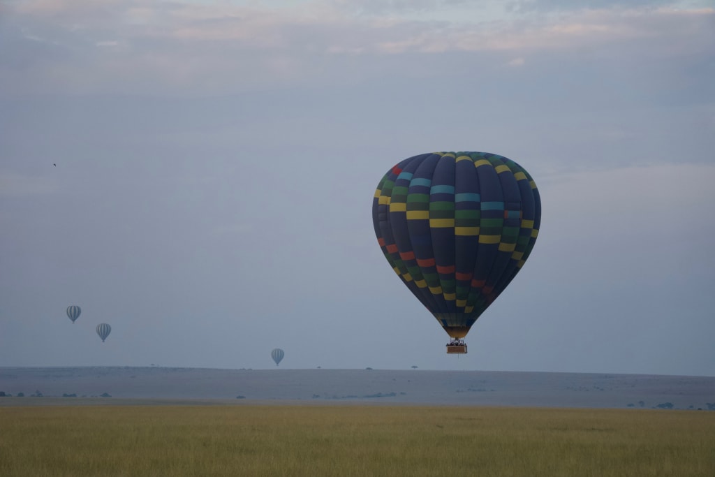 Hot air balloon floating over the Maasai Mara at sunrise