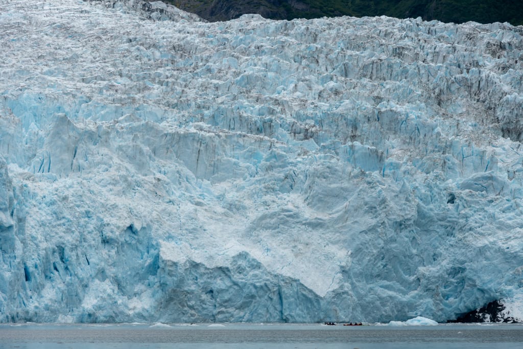 Aialik Glacier with kayaks in the distance for scale