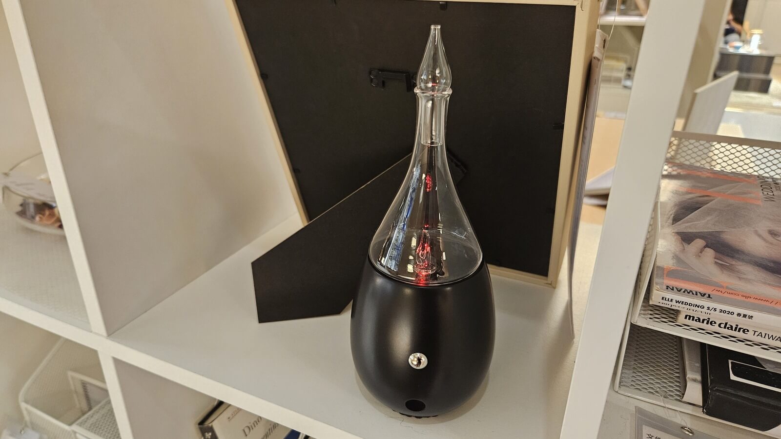 premium cold air diffuser with black wood base and glass top styled on a bookshelf