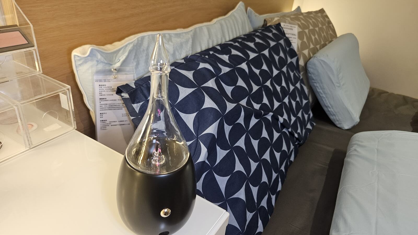 Nebulizing Diffuser on a bedside table next to navy patterned pillows in a quiet bedroom