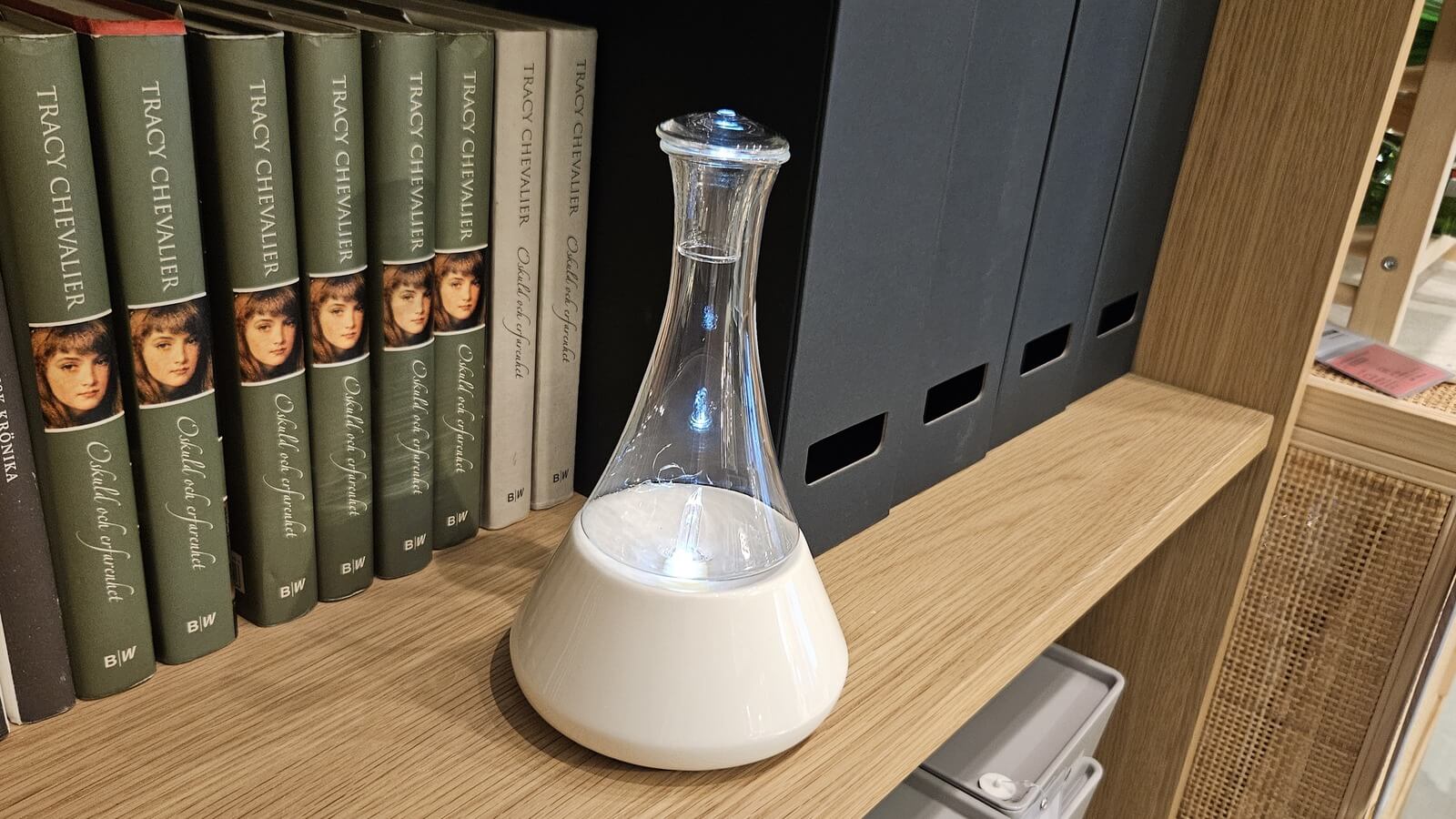 Clear glass reservoir diffuser on a bright bookshelf
