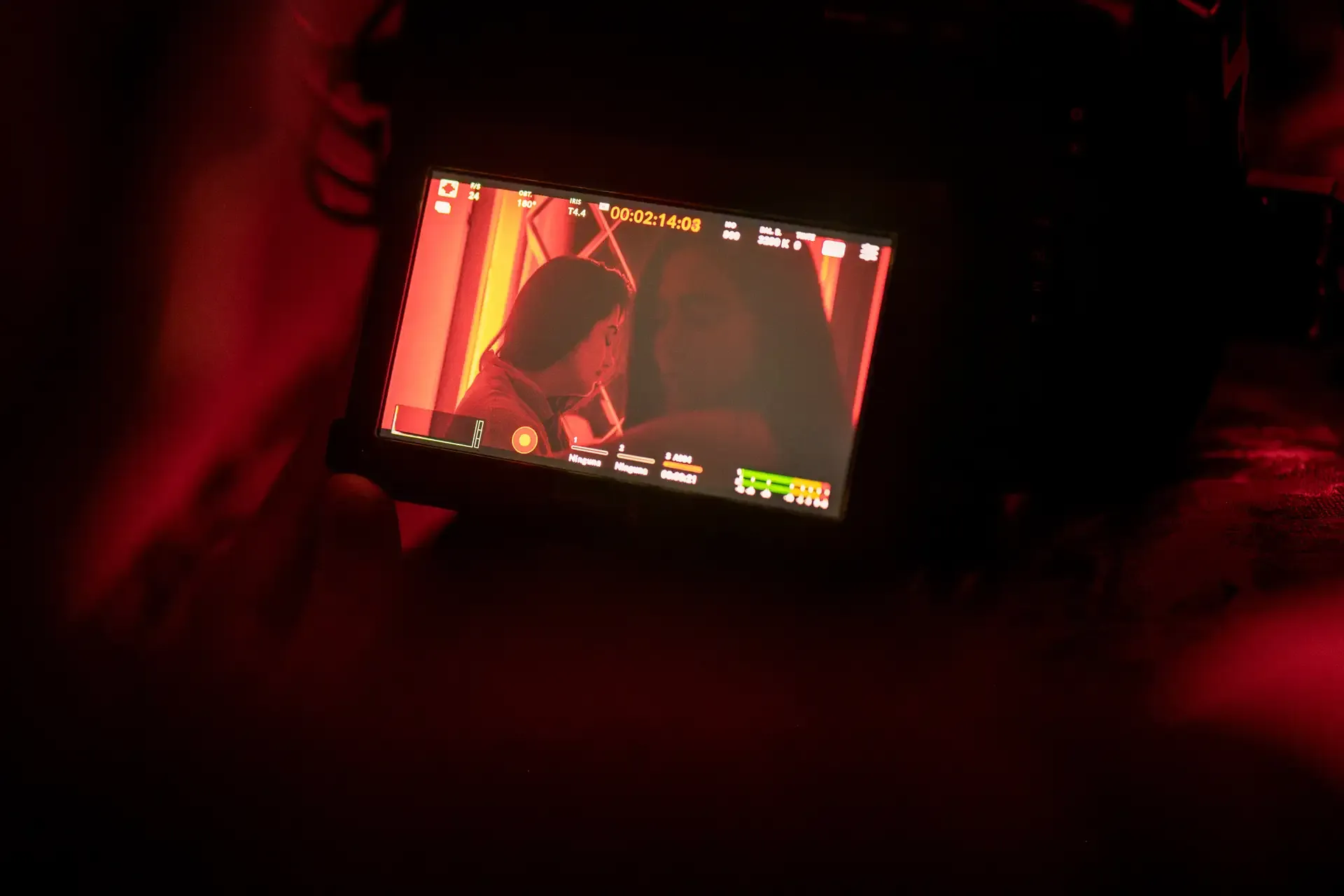 Primer plano de una cámara de cine profesional ajustando los parámetros de grabación en un set iluminado por una fuerte luz roja | DUAL PRODUCTORA