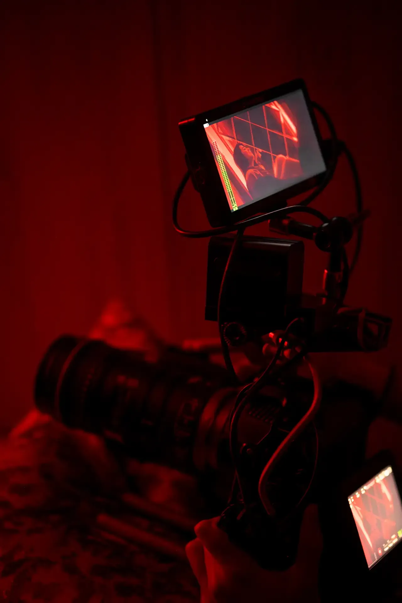 Primer plano de una cámara de cine profesional operando en un set oscuro iluminado por una fuerte luz roja | DUAL PRODUCTORA