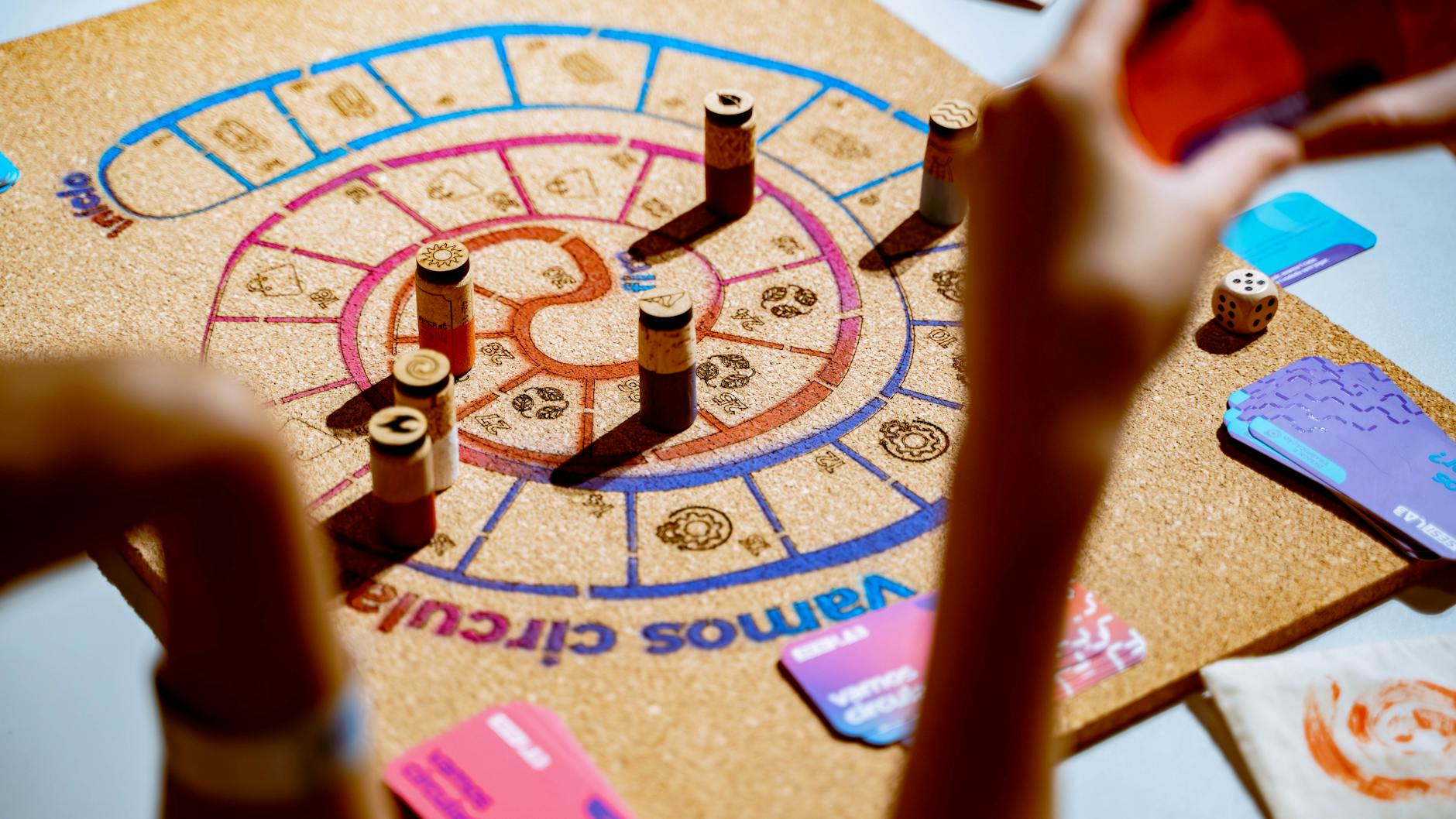Colorful board game in play with hands visible around the table