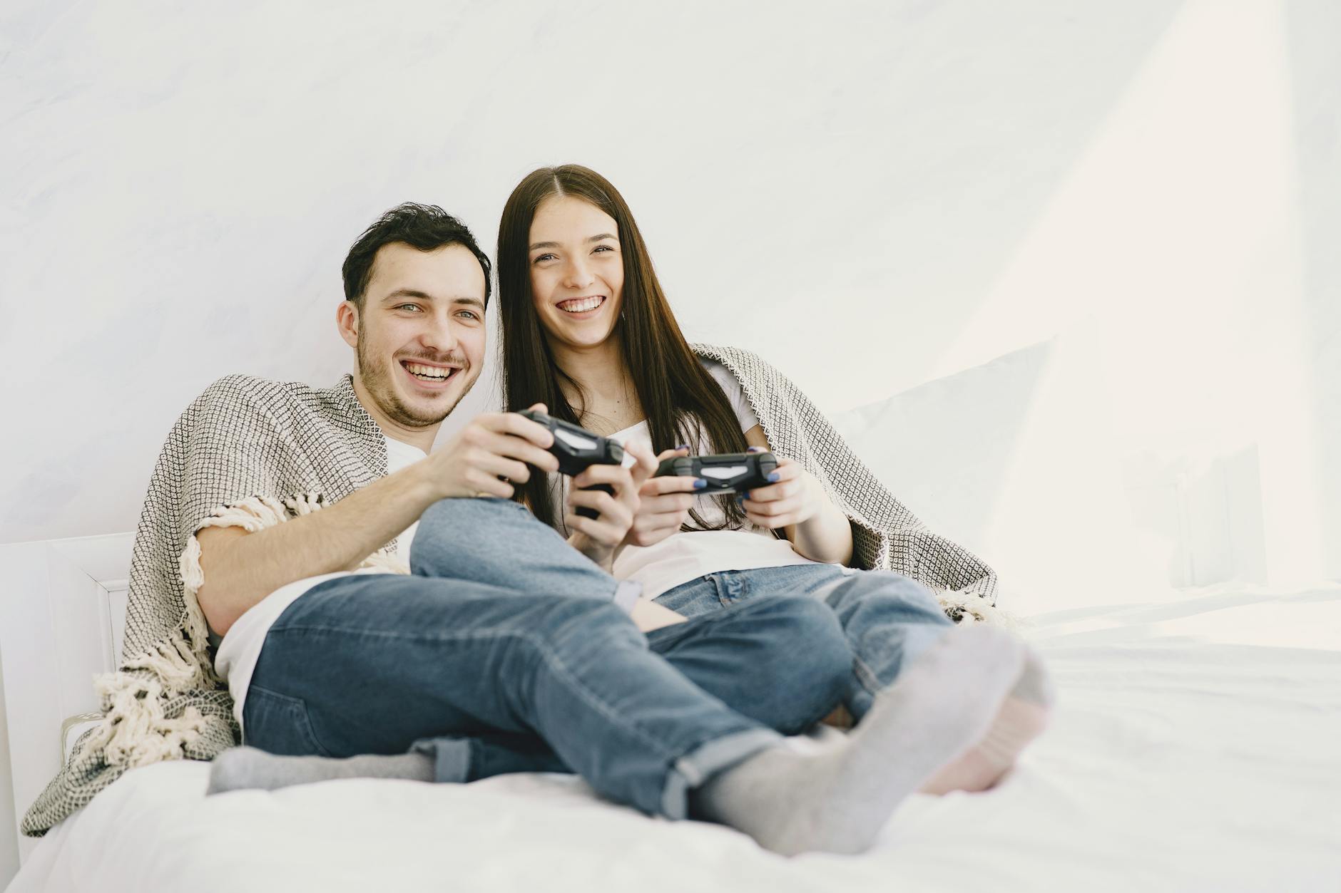 Couple cuddled together on a couch with game controllers