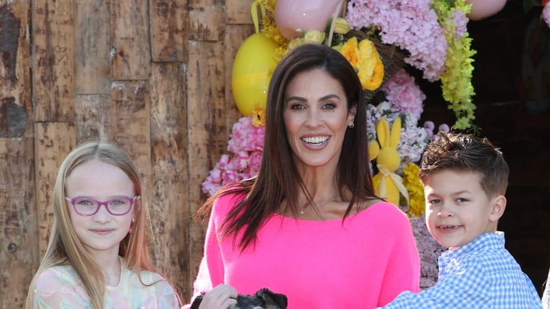 Woman in pink sweater with two children and a rabbit at an Easter event with floral decorations