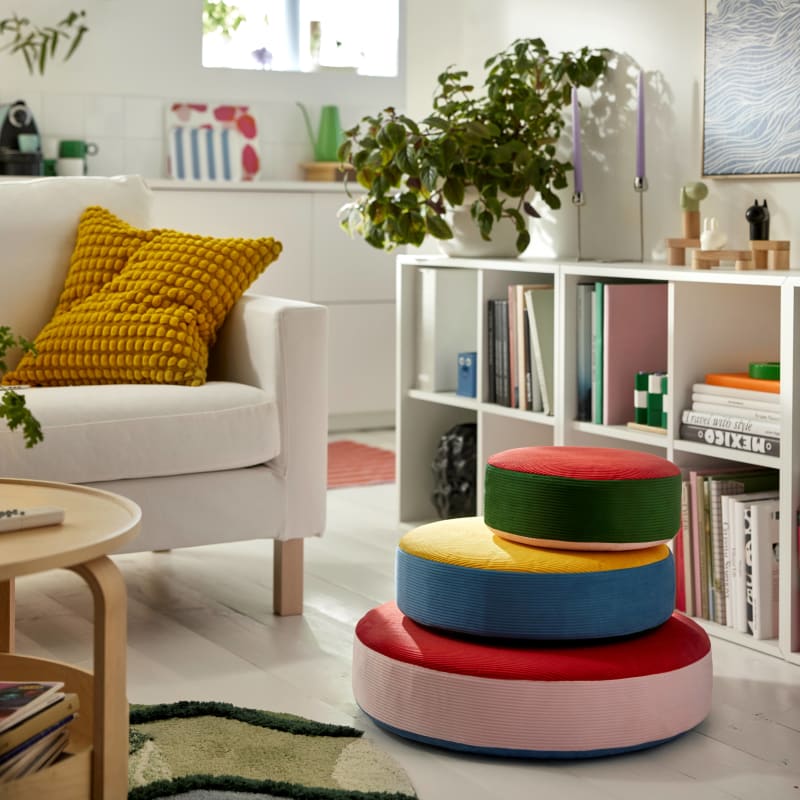 Colorful stacked floor cushions in pink, red, blue, yellow and green in a modern living room setting