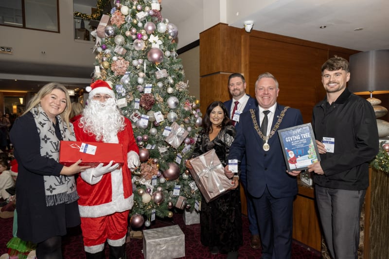 Group with Santa and Mayor posing at Giving Tree Christmas charity event in hotel lobby