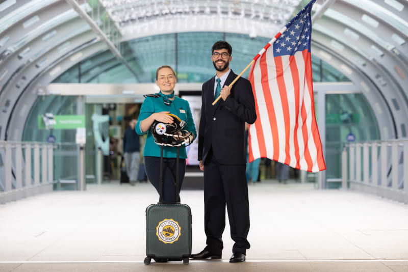 Aer Lingus staff with Pittsburgh Steelers helmet and American flag at airport terminal