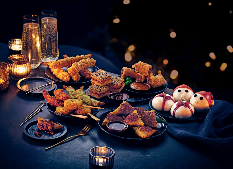 Festive party food spread with tempura prawns, samosas, spring rolls, sesame toast and snowman bao buns