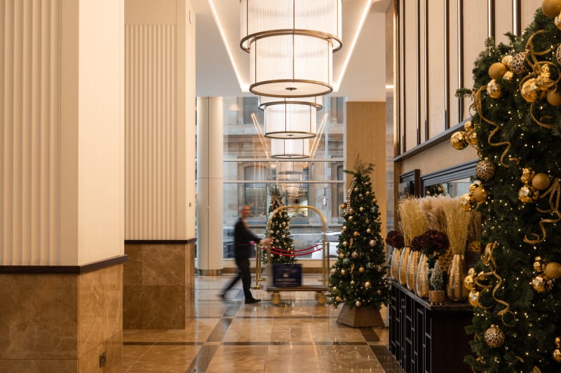 Elegant hotel lobby with Christmas trees decorated in gold ornaments and modern chandeliers