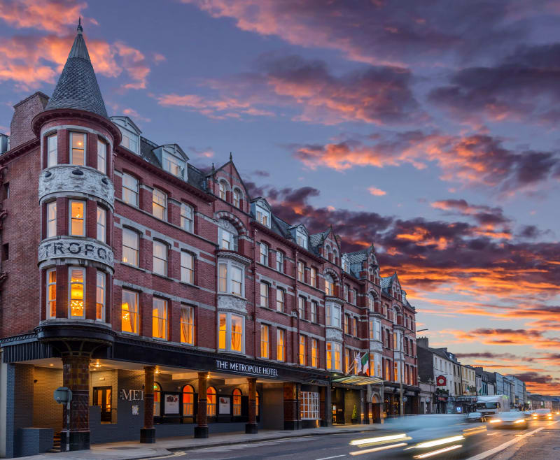 The Metropole Hotel, a Victorian red brick building with turret at dusk with dramatic sunset sky