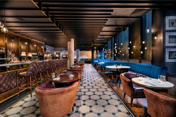 Upscale bar and restaurant interior with leather seating, geometric floor tiles, and ambient lighting