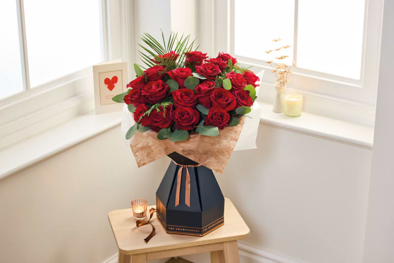 The Showstopper red rose bouquet in navy presentation box with bronze ribbon on wooden table