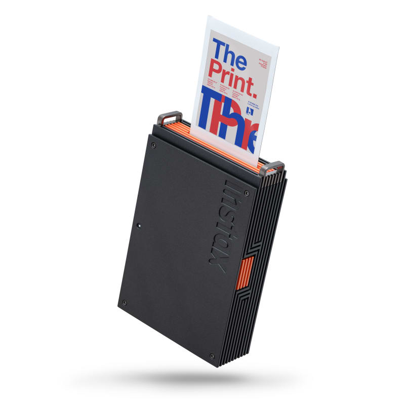 Fujifilm Instax portable photo printer in black with orange accents, printing a photo