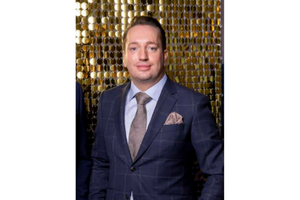 Man in navy windowpane suit with grey tie against gold sequin backdrop
