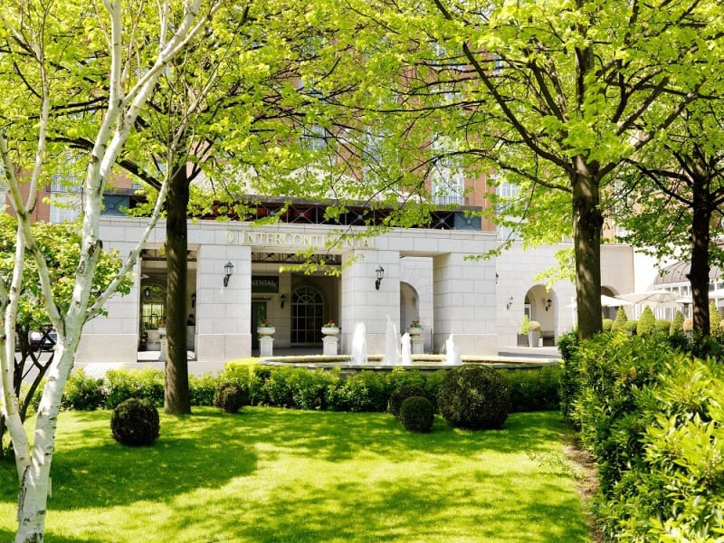 InterContinental hotel exterior with fountains, stone facade and manicured gardens framed by trees