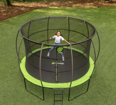 Large round trampoline with safety net and child bouncing on black mat with green padding