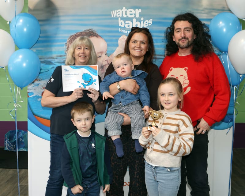 Ollie Brennan and family at Water Babies event with certificate and balloons