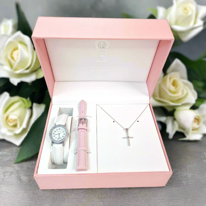 Pink jewelry gift set with watch, extra strap, and cross necklace surrounded by white roses