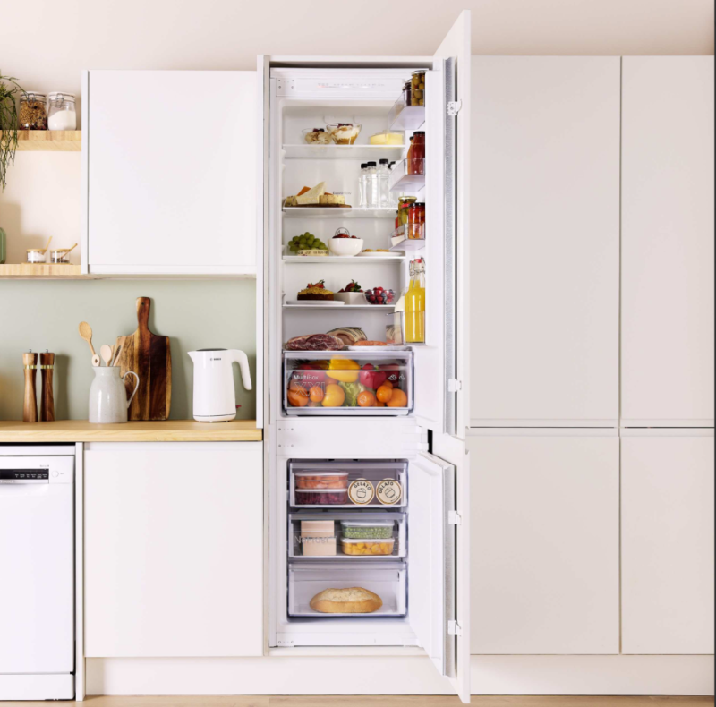 Built-in fridge-freezer open showing fully stocked shelves with fresh food, fruit, condiments and a MultiBox drawer.