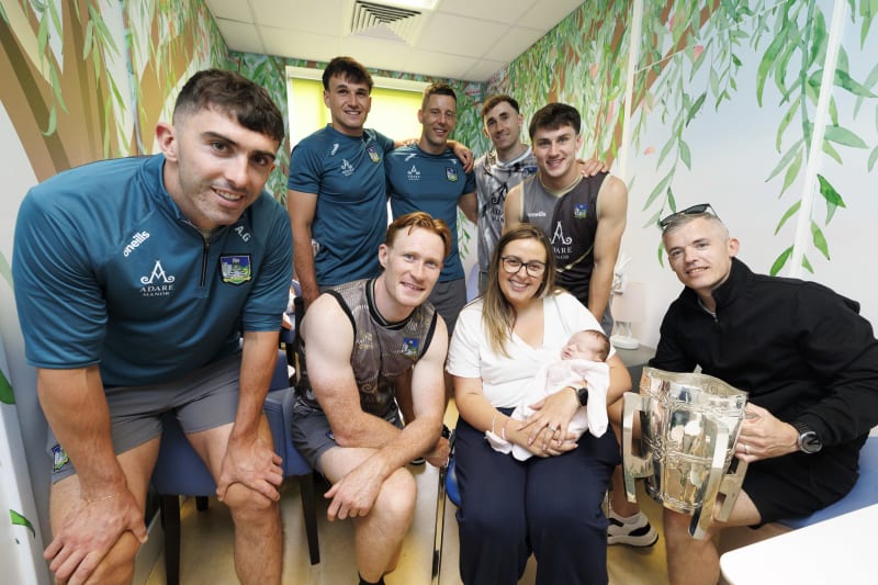 Limerick GAA players visit Crumlin Children's Hospital, posing with a mother, newborn baby and the Liam MacCarthy Cup.