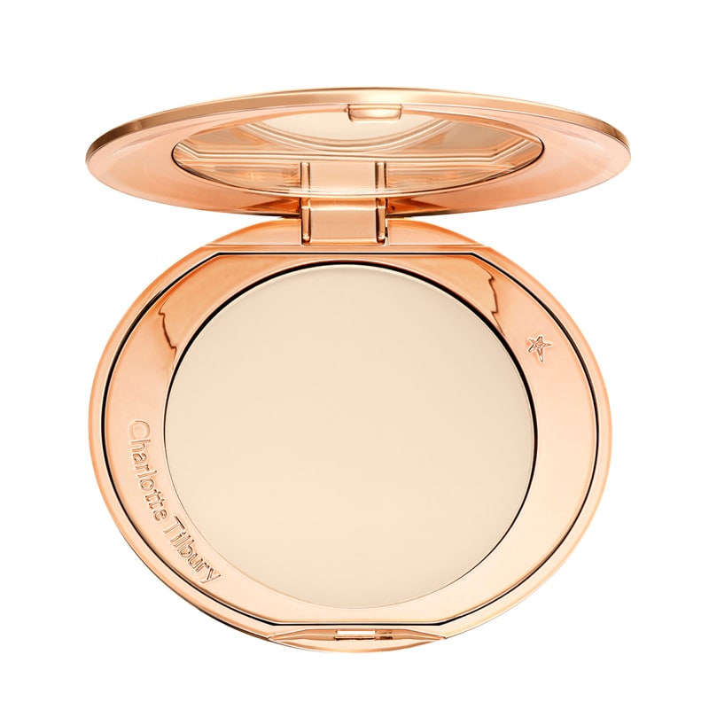 Charlotte Tilbury open rose-gold compact with large round pale pressed powder and mirror lid.