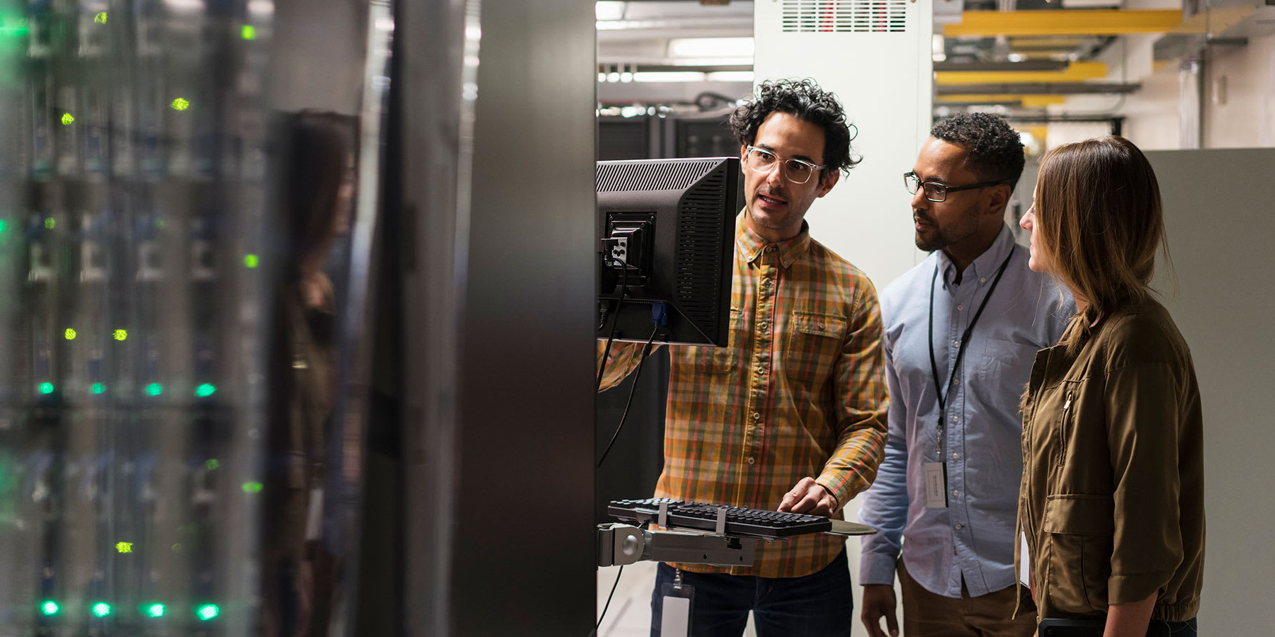 Women and two men looking at a monitor in a server room.