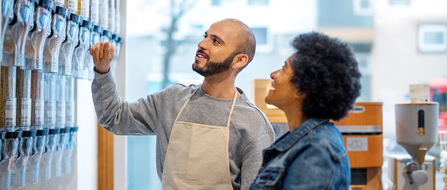 Grocery worker helping elder woman customer in bulk item section