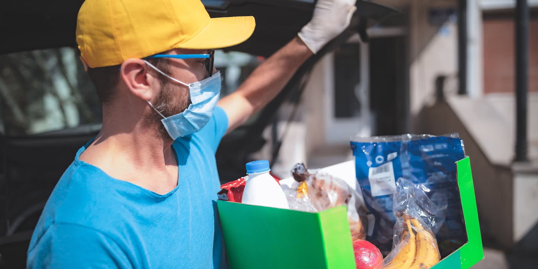 Man delivering a package of food with a mask and gloves on for social distancing