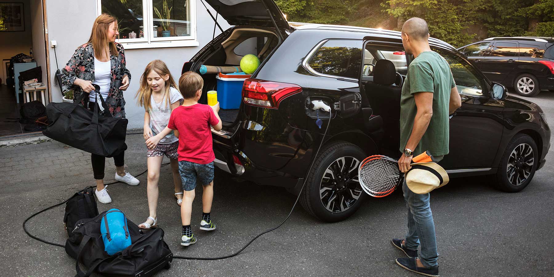 Family loading up their electric car while it is plugged in and charging