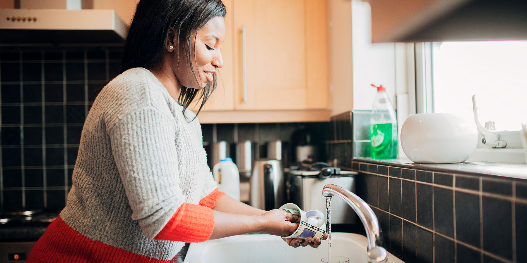 Woman washing dishes in her kitchen sink.