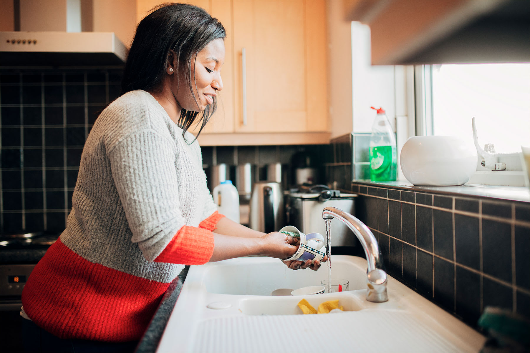 Woman washing dishes in her kitchen sink.