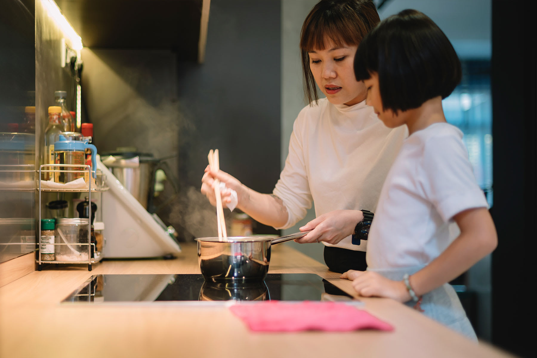 Mother and daughter cooking food on their home induction stove.