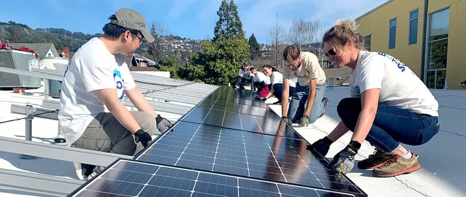 Grant recipients installing solar panels on a roof top