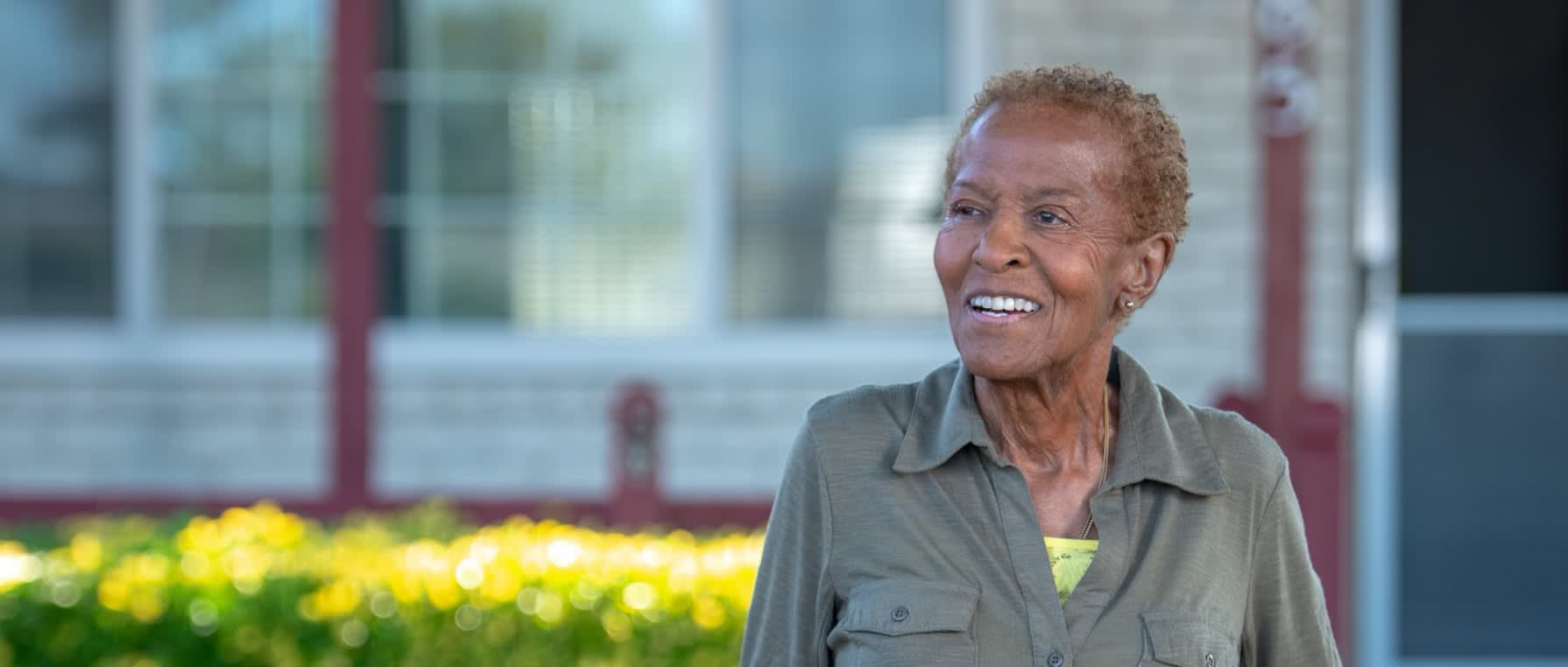 Picture of an African American elderly woman outside her home smiling.