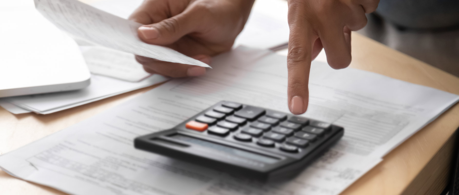 Hand using a calculator on table with papers