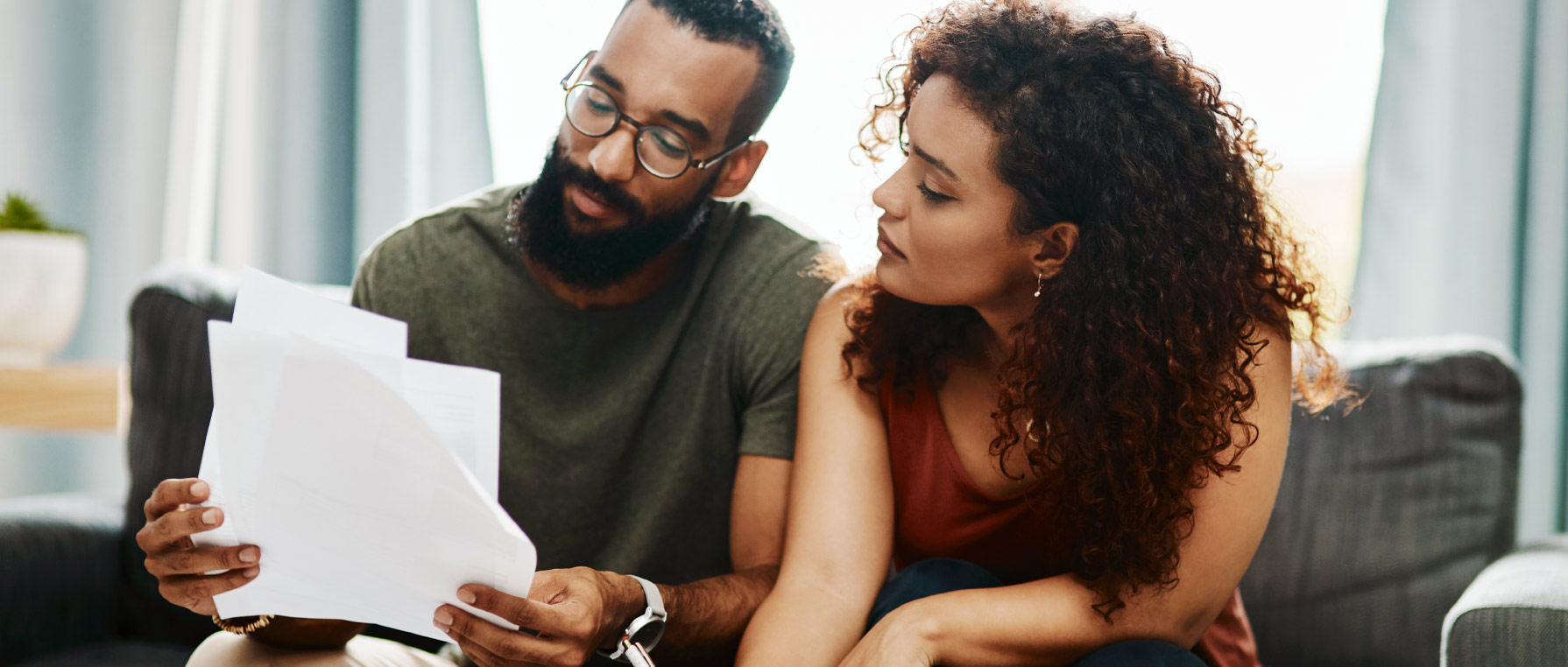 Couple reviewing paper bills on a couch