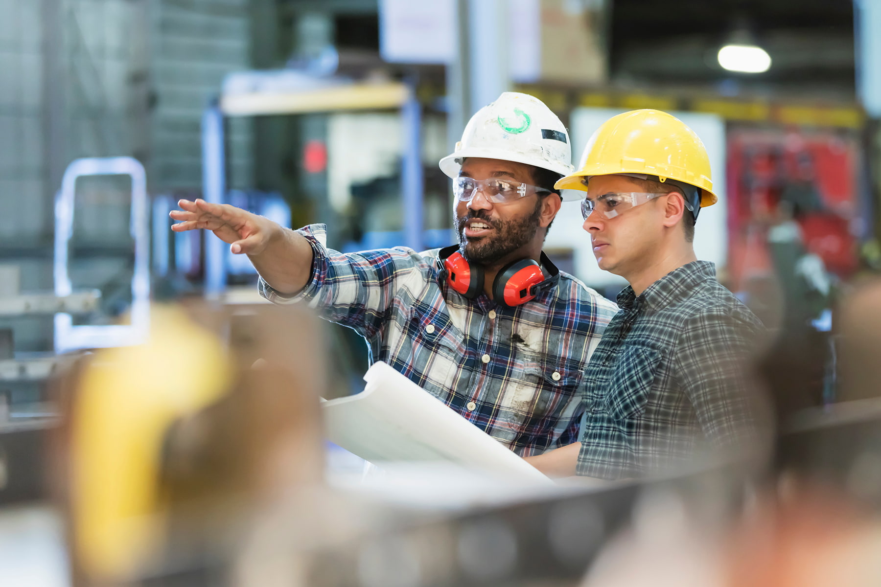 Two men in hard hats in a factory talking