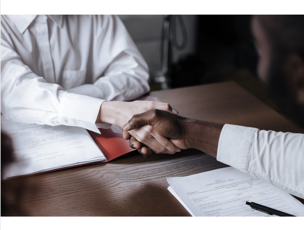 White and Black hand shake over important papers