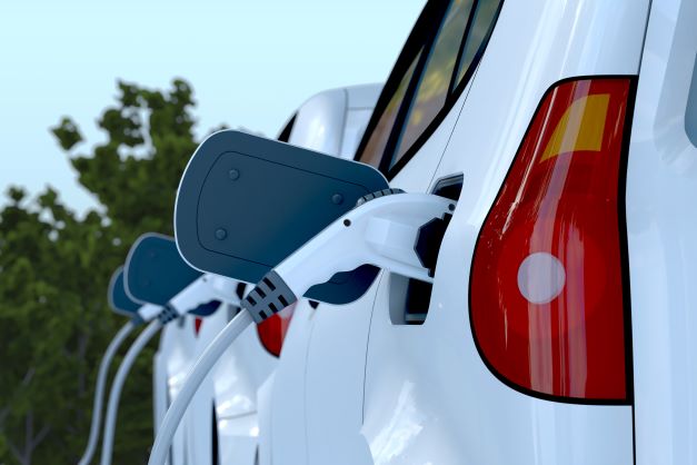 Photo of several white cars plugged in and being charged with electricity